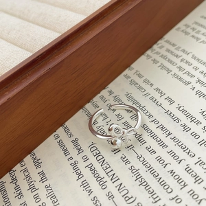 Macro dell'anello a fiocco in argento S925 lucido con perla su sfondo di carta scritta