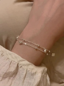Gros plan d'un bracelet double couche en argent avec cœurs et perles sur un poignet