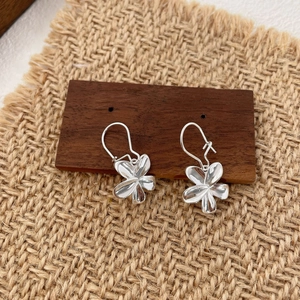 Detailed view of silver petal earrings with high-polish finish on rustic linen cloth