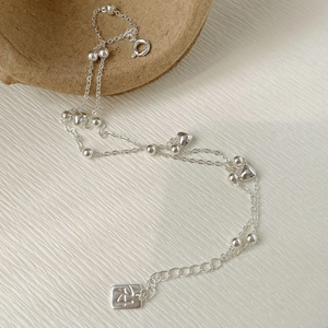 Gros plan du poinçon S925 et du pendentif coeur sur le bracelet double couche en argent