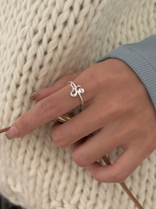 Dettaglio dell'anello con fiocco in argento S925 indossato con un maglione lavorato