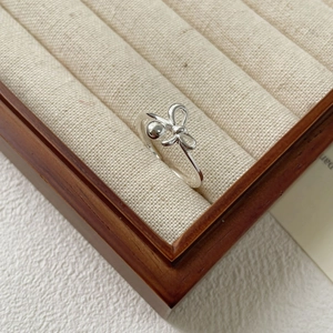 Anello con fiocco in argento sterling S925 e perla esposto in una scatola di velluto beige