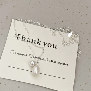 Detail of S925 silver necklace featuring a round bead and drop pearl pendant on a card
