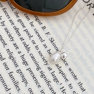 Detail of baroque pearl and polished silver bead pendant on a delicate s925 silver chain