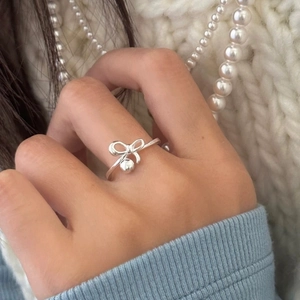 Elegante anello a fiocco in argento S925 con perla pendente su mano femminile