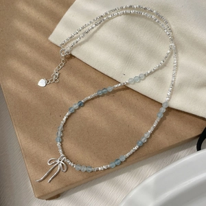 Detail of S925 silver beaded necklace with blue aquamarine gems and bow pendant