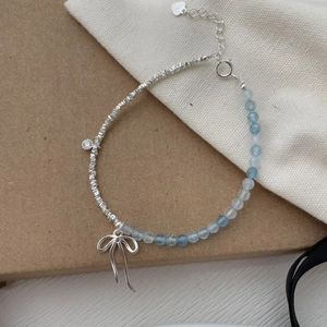 Detailed shot of S925 silver bracelet with blue aquamarine beads and bow charm