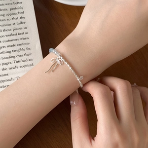 Close-up of S925 silver bracelet with blue crystal beads and bow pendant on wrist