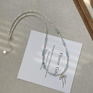 Detail of S925 silver beaded necklace featuring a blue gemstone and bow pendant charm