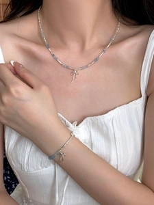 Detail of S925 silver beaded necklace and bracelet set with light blue stones and bows