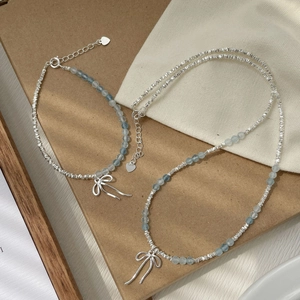 Detailed macro view of S925 silver beaded bracelet with blue aquamarine and bow pendant