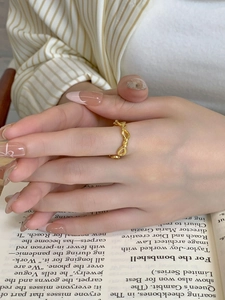 Close-up of minimalist gold twisted rope ring on finger with elegant aesthetic