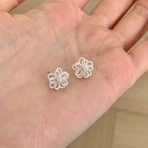 Detailansicht der S925 Silber Blumenohrstecker mit feiner Perlenstruktur auf der Hand