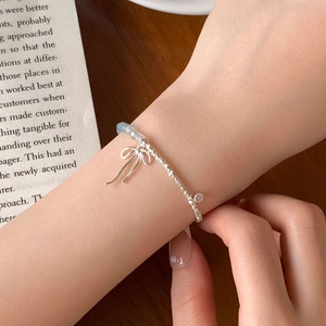 Handmade S925 silver bracelet with blue beads and bow pendant on a person's wrist