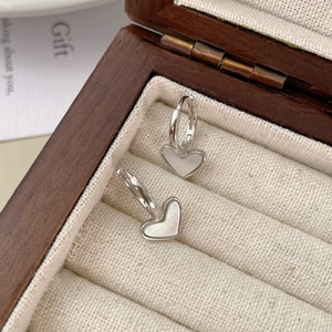 Macro shot of S925 silver heart earrings with mother of pearl inlay on rustic linen