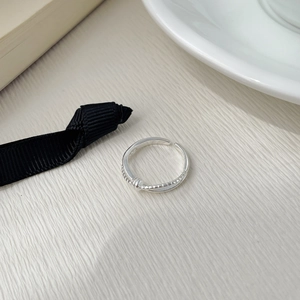 Detailed close-up of a 925 sterling silver braided knot ring on white textured surface