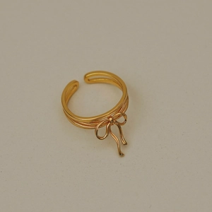 Detailed close-up of a polished gold ribbon bow ring with an adjustable open band design