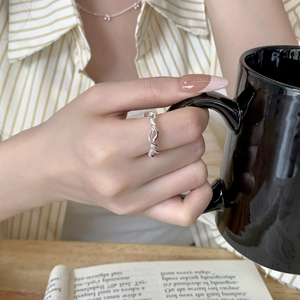 Detailed close-up of a twisted S925 silver ring worn while holding a black mug