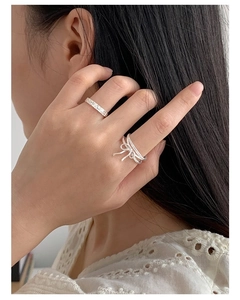 Detailed view of S925 sterling silver ribbon bow ring and hammered texture band on finger