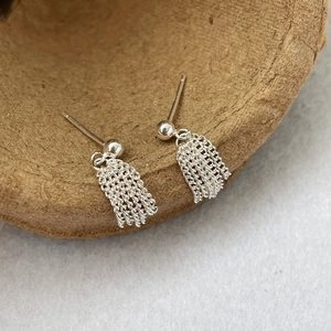 Macro detail of S925 sterling silver tassel earrings with five delicate chains on fabric