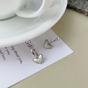 Close-up of silver heart-shaped hoop earrings with white mother of pearl inlay
