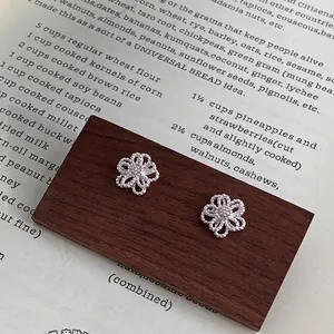 Elegante S925 Silber Hohlblumen Ohrstecker mit Diamanten auf einem Holzdisplay