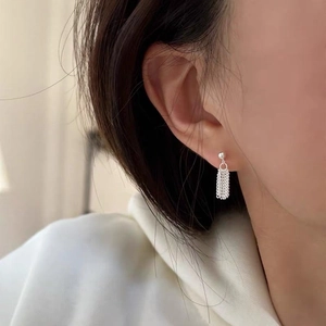 Minimalist S925 sterling silver chain tassel stud earrings worn by a model in soft light