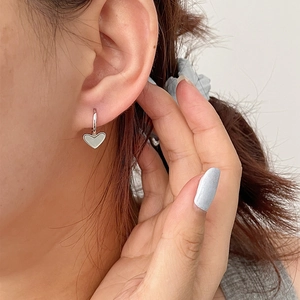 Minimalist S925 sterling silver heart hoop earrings worn by a model in a close-up shot