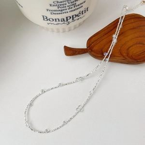Vue détaillée d'un collier en argent S925 avec perles irisées sur plateau en bois