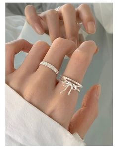 Close-up of S925 silver layered bow ring and pavé band with elegant mirror reflection
