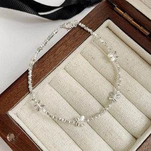 Macro detail of S925 silver bow bracelet with irregular bead texture in a gift box