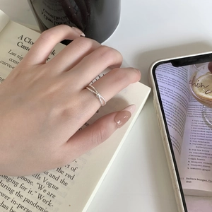 Macro shot of minimalist S925 sterling silver knot ring worn on a finger over a book