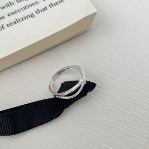 Close-up of S925 sterling silver knotted ring with woven texture on a black ribbon