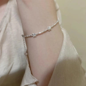 Detailed close-up of a silver beaded bracelet with delicate butterfly charms on a wrist