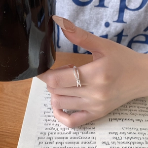 Close-up of minimalist S925 sterling silver twisted knot ring on finger with coffee cup
