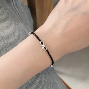 Détail du bracelet en argent S925 avec perles de spinelle noire et breloques nœuds au poignet