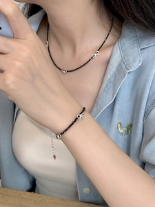 Gros plan d'un ensemble collier et bracelet en perles noires avec nœuds en argent