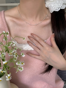 Gros plan d'un délicat collier de perles en argent S925 porté sur le cou d'une femme