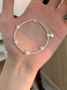 Close-up of S925 sterling silver beaded bracelet featuring detailed butterfly charms on hand