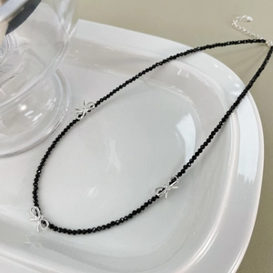Détails du collier en spinelle noire avec des breloques nœuds argentés et fermoir réglable