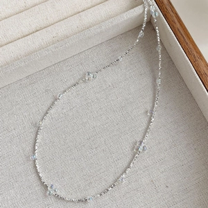 Détail macro d'une fine chaîne en argent S925 avec des perles bulles irisées colorées