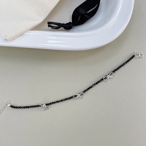 Vue détaillée d'un bracelet en perles de spinelle noire avec trois breloques nœuds