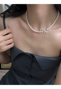 Elegant pearl necklace with silver bow pendant shown on a model's collarbone