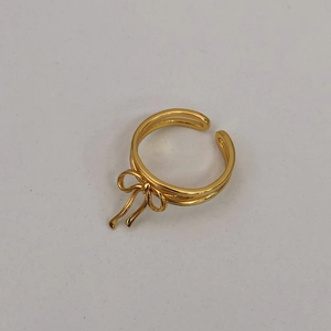 Detail of a gold ribbon bow ring with double-line adjustable band design