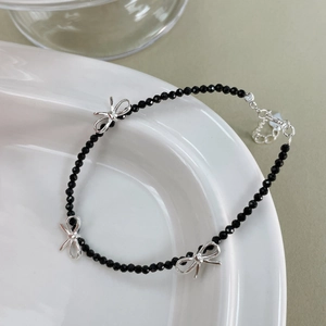 Détail macro d'un bracelet de perles noires facettées avec des nœuds argentés fins