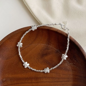 S925 silver beaded bracelet with butterfly charms on a rustic wooden plate background