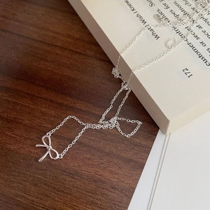 Detailaufnahme der S925 Silber Schleife Halskette auf Vintage Buch und Holztisch