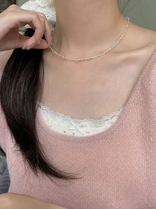 Délicat collier en argent S925 à perles porté par un mannequin en pull rose pastel