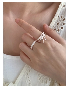 Detail of S925 sterling silver bow ring set with zircons on model finger with lace background