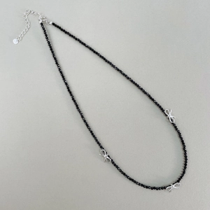 Vue macro des pendentifs nœud en argent S925 et chaîne perlée en spinelle noire